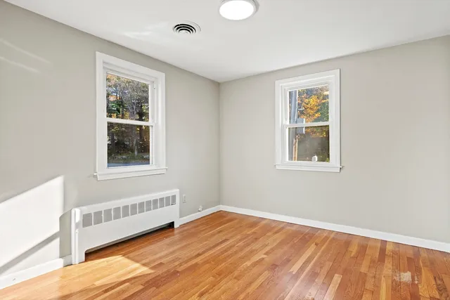 a view of an empty room with a window and wooden floor