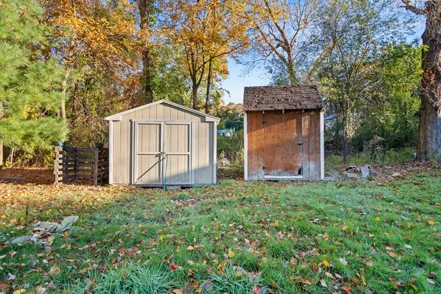 a backyard of a house with plants and large tree
