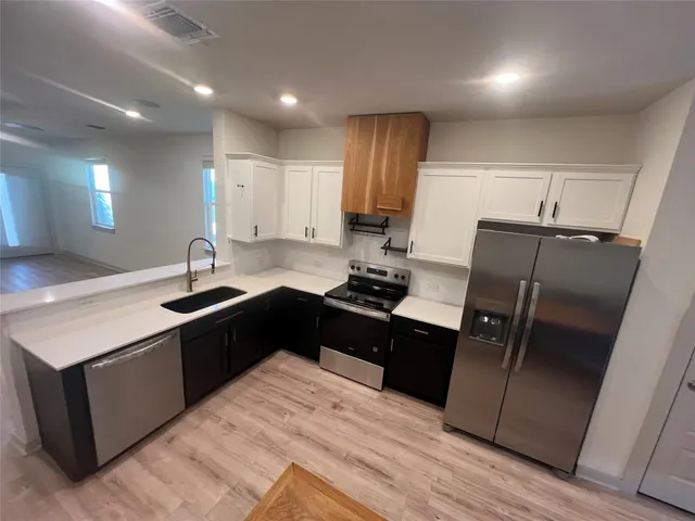 a kitchen with granite countertop a refrigerator sink and cabinets