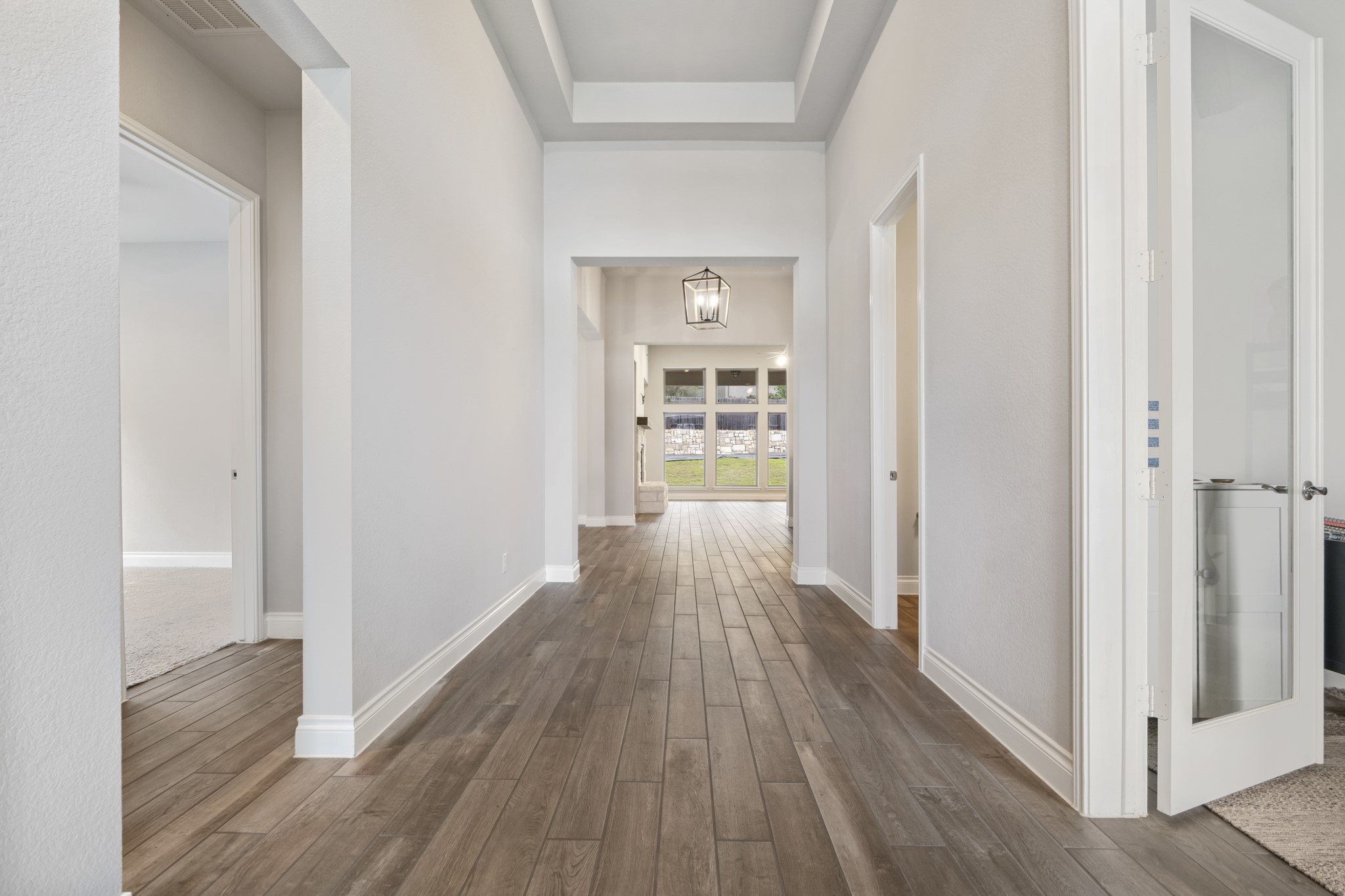 104 Catani Loop Georgetown, TX 78628 - Photo 16 of 34 The property features an entryway with wood-look tile flooring, light-colored walls, and a decorative ceiling fixture