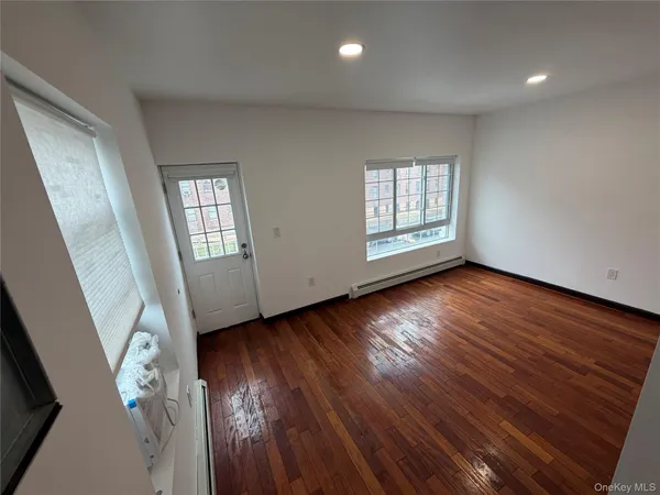 a view of an empty room with wooden floor and window