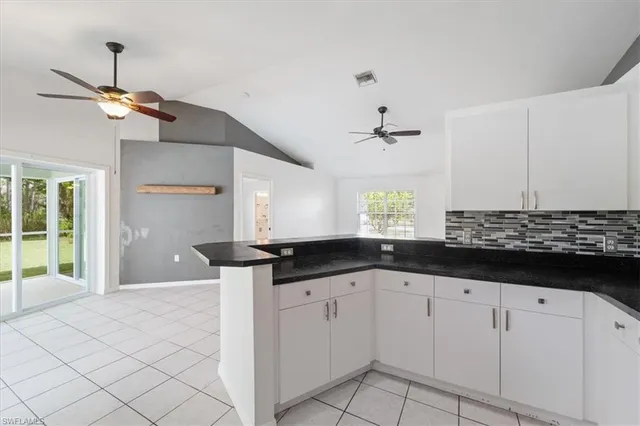 a kitchen with white cabinets and chandelier