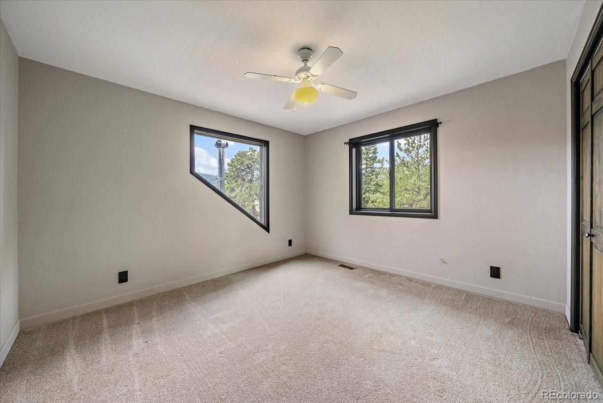 32482 Lodgepole Drive Evergreen, CO 80439 - Photo 20 of 40 an empty room with windows and chandelier fan