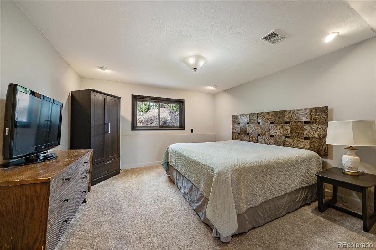 32482 Lodgepole Drive Evergreen, CO 80439 - Photo 26 of 40 a bedroom with a large bed and a flat screen tv