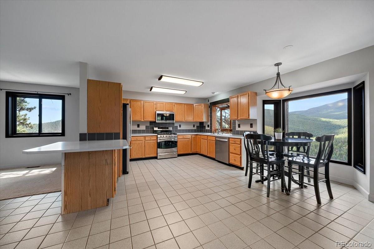 32482 Lodgepole Drive Evergreen, CO 80439 - Photo 7 of 40 a kitchen with stainless steel appliances kitchen island granite countertop a sink counter space and chairs in it