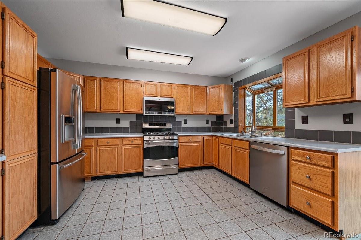 32482 Lodgepole Drive Evergreen, CO 80439 - Photo 8 of 40 a kitchen with stainless steel appliances granite countertop a refrigerator and wooden cabinets