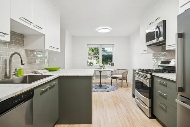 a kitchen with stainless steel appliances a sink dishwasher a stove top oven a refrigerator with wooden floor and cabinets