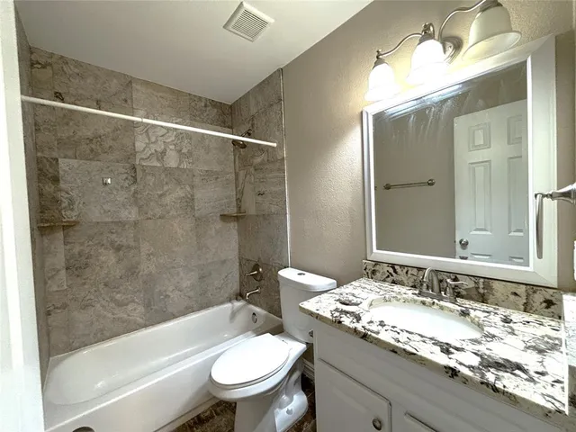 a bathroom with a granite countertop sink toilet mirror and bathtub