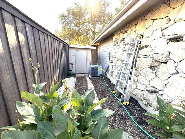 a backyard of a house with large trees and plants