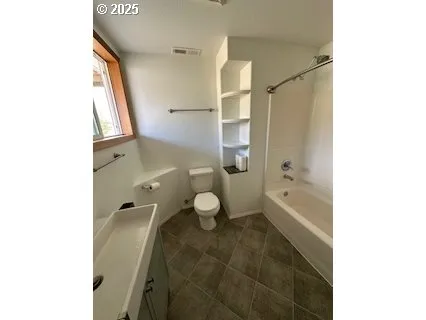 a bathroom with a granite countertop bathtub shower sink mirror and toilet