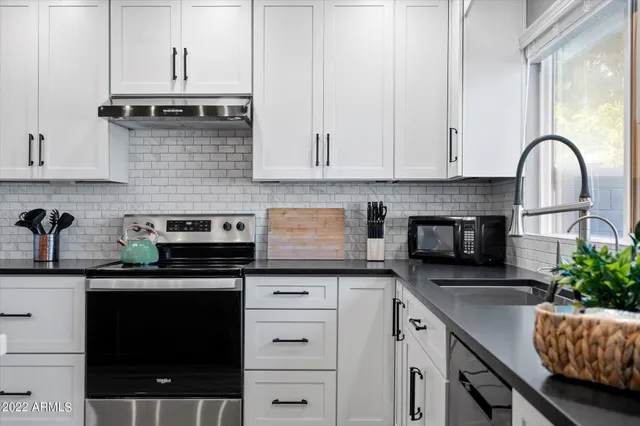 a kitchen with granite countertop a stove sink and cabinets