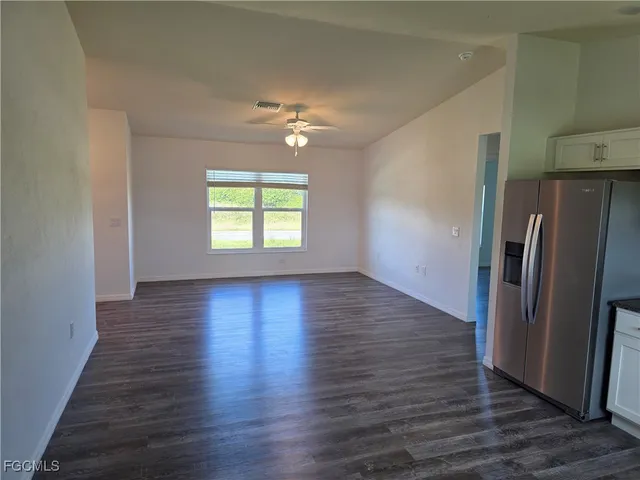 an empty room with wooden floor a ceiling fan and windows