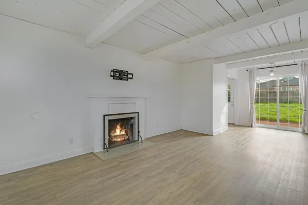 an empty room with wooden floor fireplace and windows