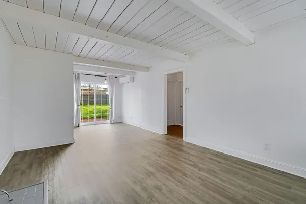 a view of an empty room with a window and wooden floor