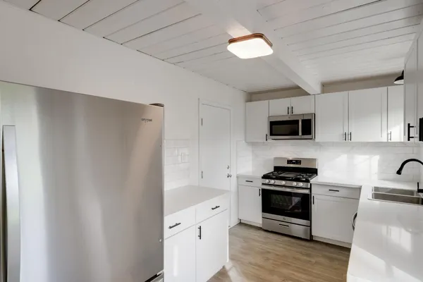 a kitchen with stainless steel appliances a stove a microwave and a hard wood floors