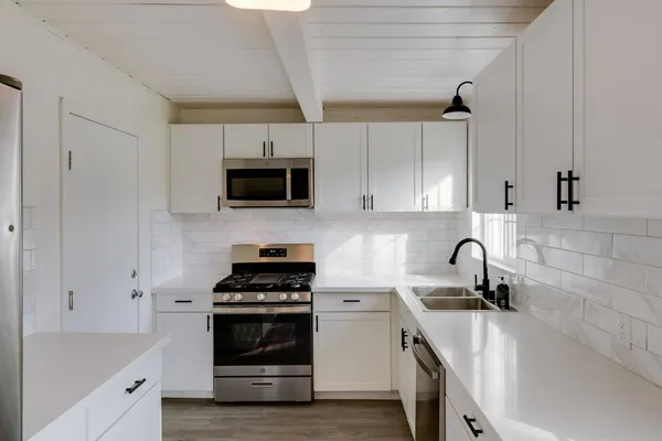 a kitchen with stainless steel appliances a stove a sink a microwave and cabinets
