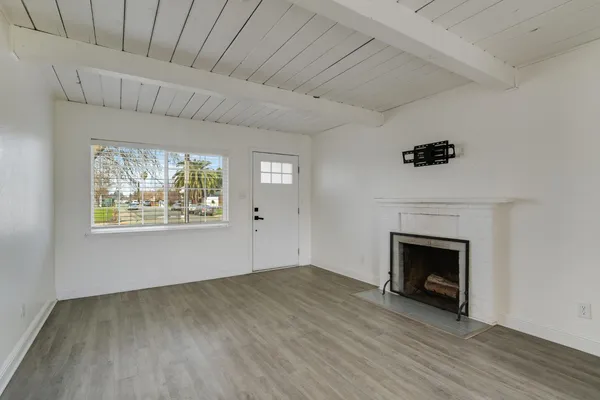 a view of empty room with wooden floor and fireplace