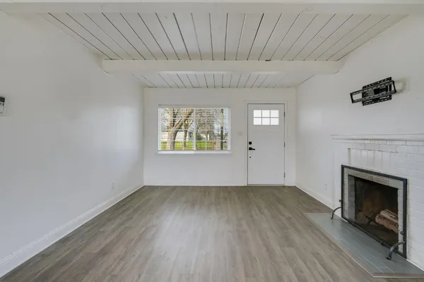 a view of an empty room with a fireplace and a window