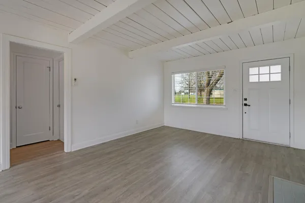 an empty room with wooden floor closet and windows
