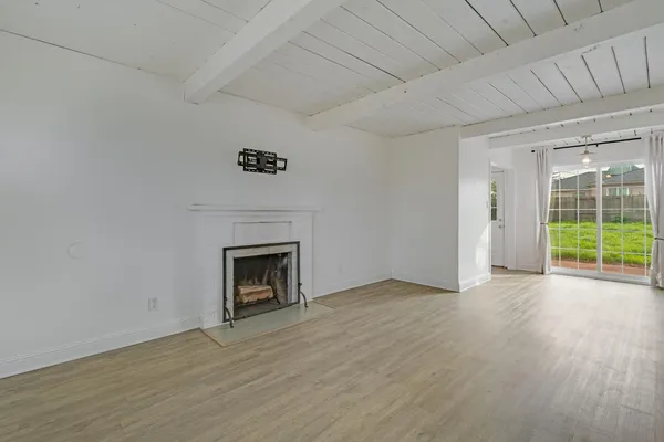 an empty room with wooden floor fireplace and windows