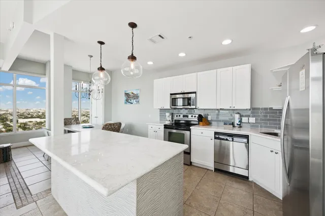 a large kitchen with kitchen island white cabinets and stainless steel appliances