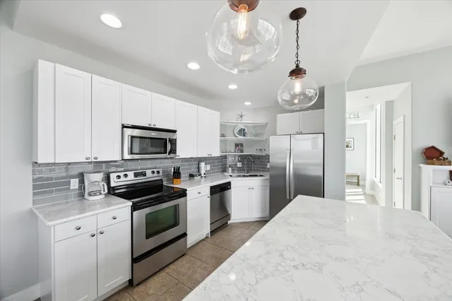 a kitchen with stainless steel appliances granite countertop a sink a stove a refrigerator cabinets and a window