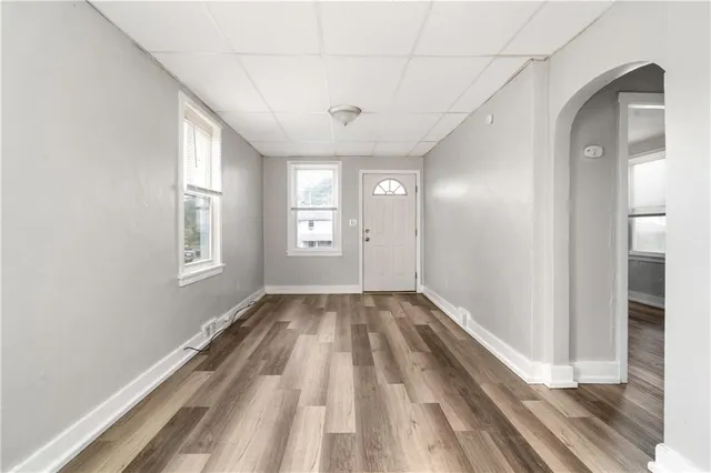 a view of hallway with window and wooden floor