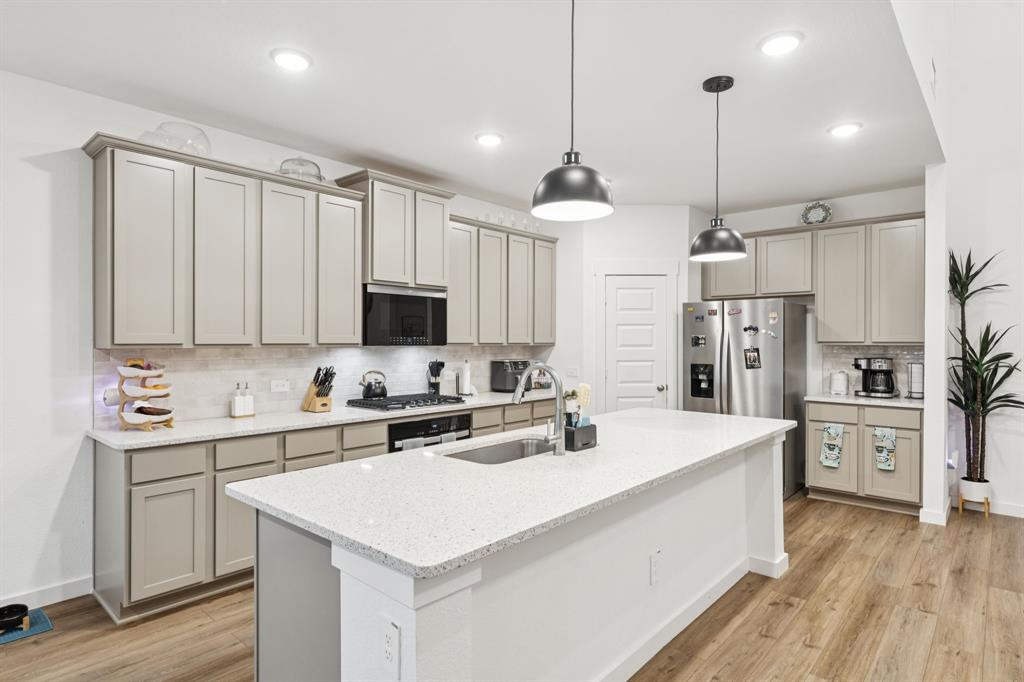 1238 Beaumont Lane Red Oak, TX 75154 - Photo 7 of 29 a kitchen with stainless steel appliances a stove a sink a refrigerator a center island and cabinets