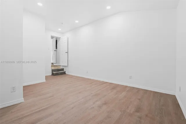 a view of empty room with window and wooden floor