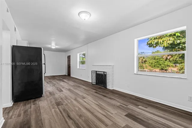 an empty room with wooden floor chandelier fan and windows