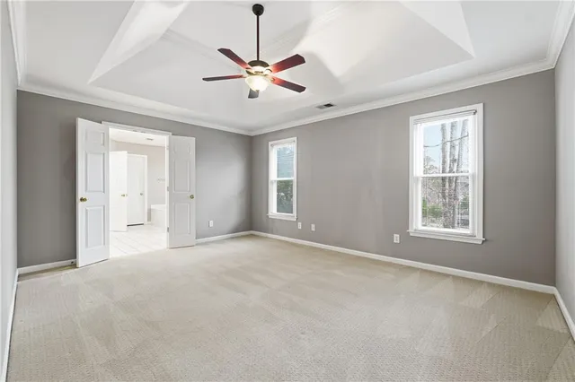 an empty room with chandelier fan and windows