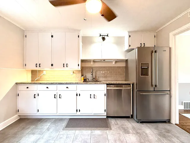 a large white kitchen with stainless steel appliances granite countertop a stove and a refrigerator