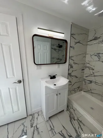 a bathroom with a tub sink and mirror