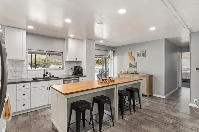 a kitchen with stainless steel appliances granite countertop a table chairs sink refrigerator and microwave