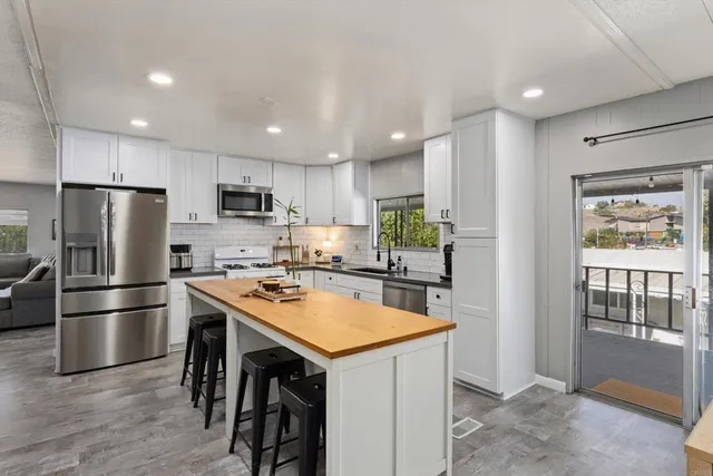 a kitchen with a refrigerator a microwave a stove and a sink with wooden floor