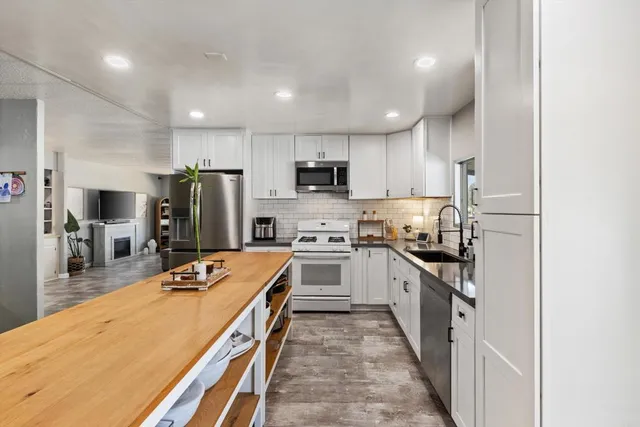 a kitchen with stainless steel appliances granite countertop a sink refrigerator and cabinets