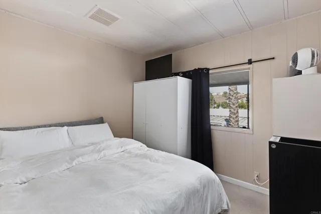 a bedroom with a bed and a refrigerator