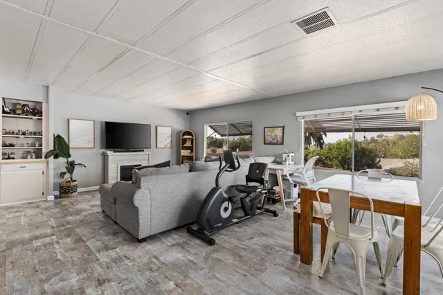 a living room with furniture a flat screen tv and floor to ceiling window