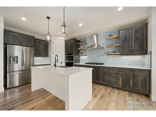 a kitchen with a refrigerator a sink and wooden floor