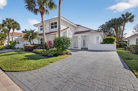 a front view of a house with a garden and palm trees