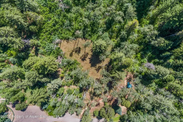 an aerial view of residential house with outdoor space and trees all around