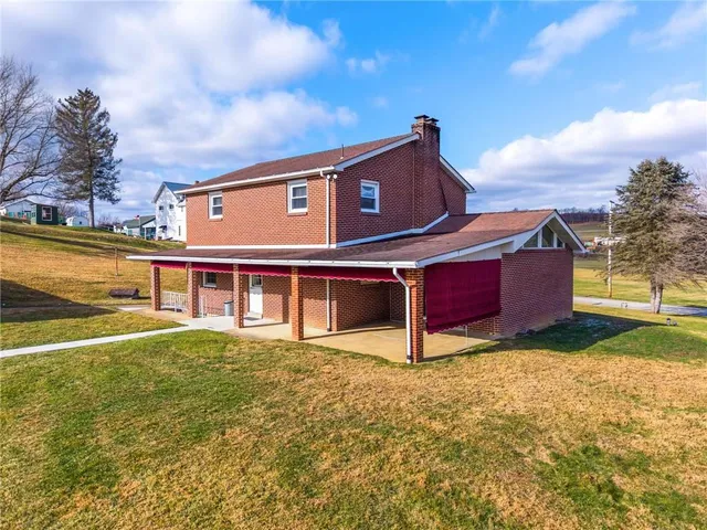a view of a big house with a big yard and large trees