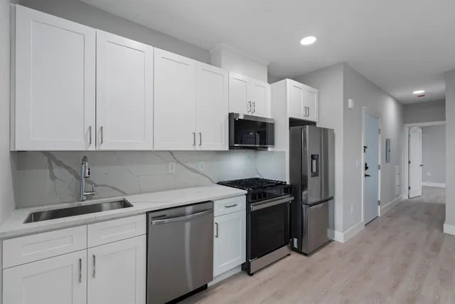 a kitchen with white cabinets and stainless steel appliances