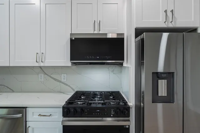 a kitchen with stainless steel appliances granite countertop white cabinets and black stove top oven with granite countertops
