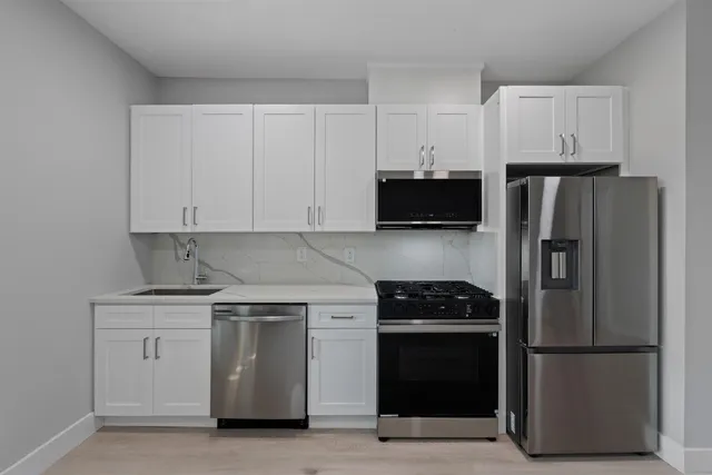 a kitchen with white cabinets and stainless steel appliances