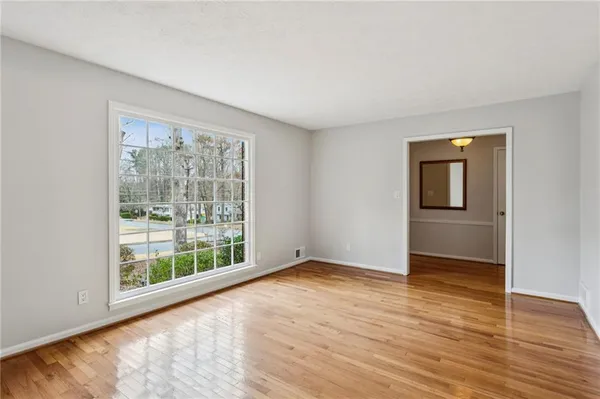 a view of an empty room with wooden floor and a window