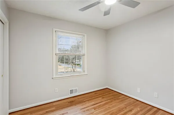 an empty room with wooden floor chandelier fan and windows