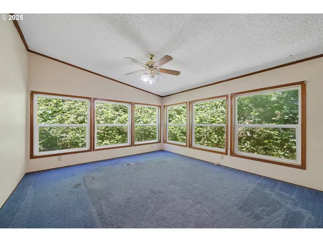 a view of an empty room with a window and a ceiling fan