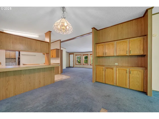 a view of an empty room with a window and kitchen view