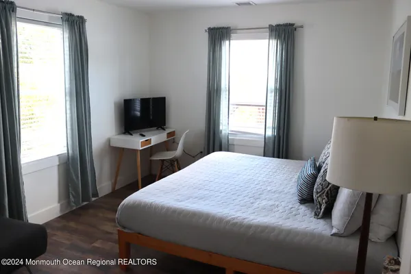a bedroom with a bed tv and a window